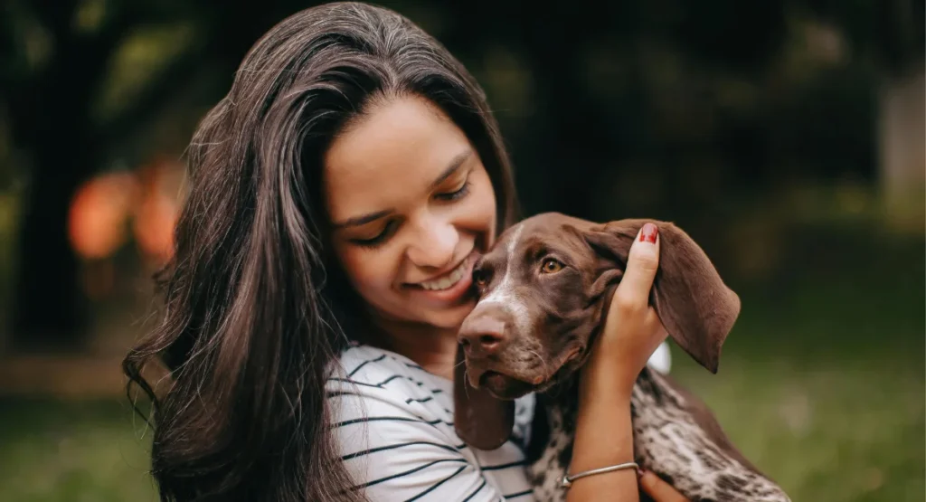 chica consintiedo a un perro orejon imagen